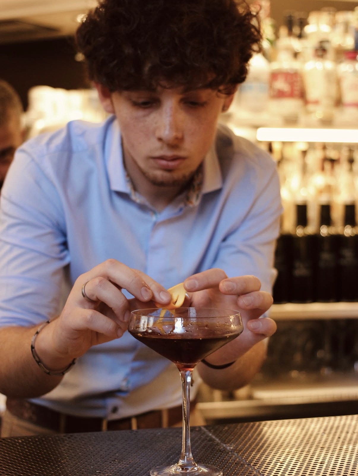 Bartender guarnisce un martini con scorza d'arancia