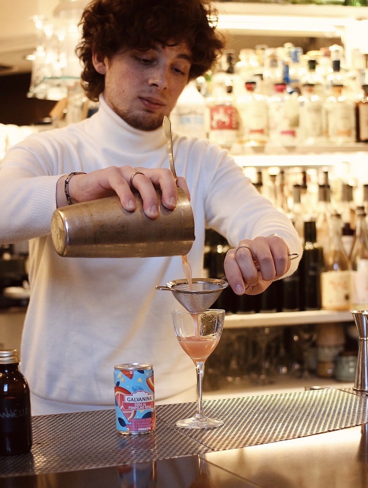 Bartender filtra un cocktail rosa