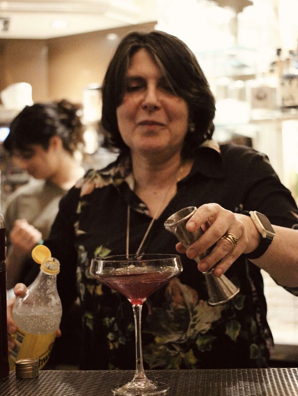 Bartender aggiunge una misura a un cocktail rosso